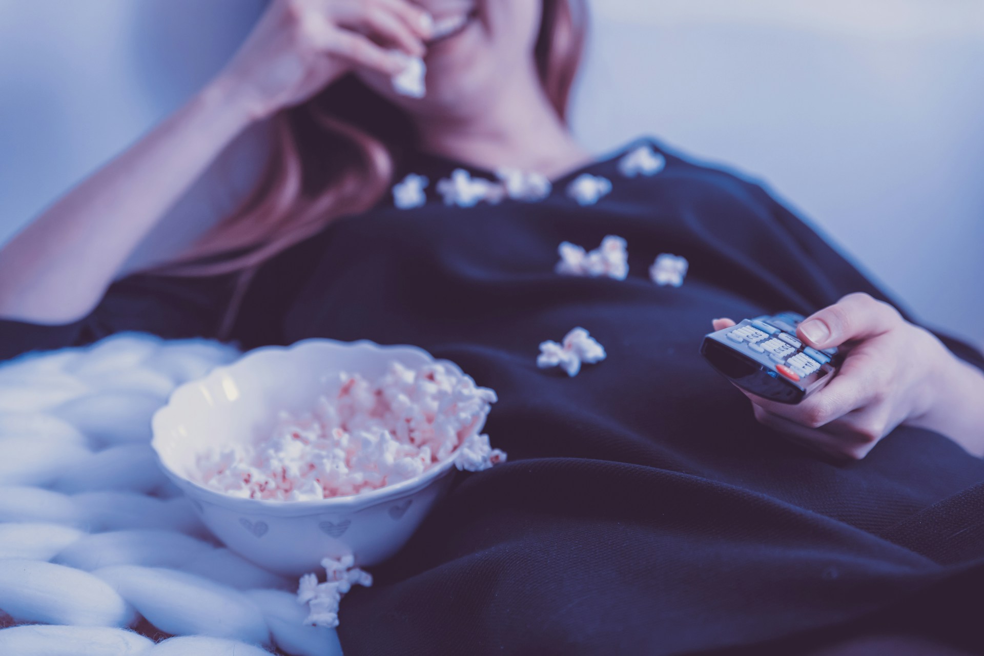 Women eating popcorn on a bed after taking a cannabis edible